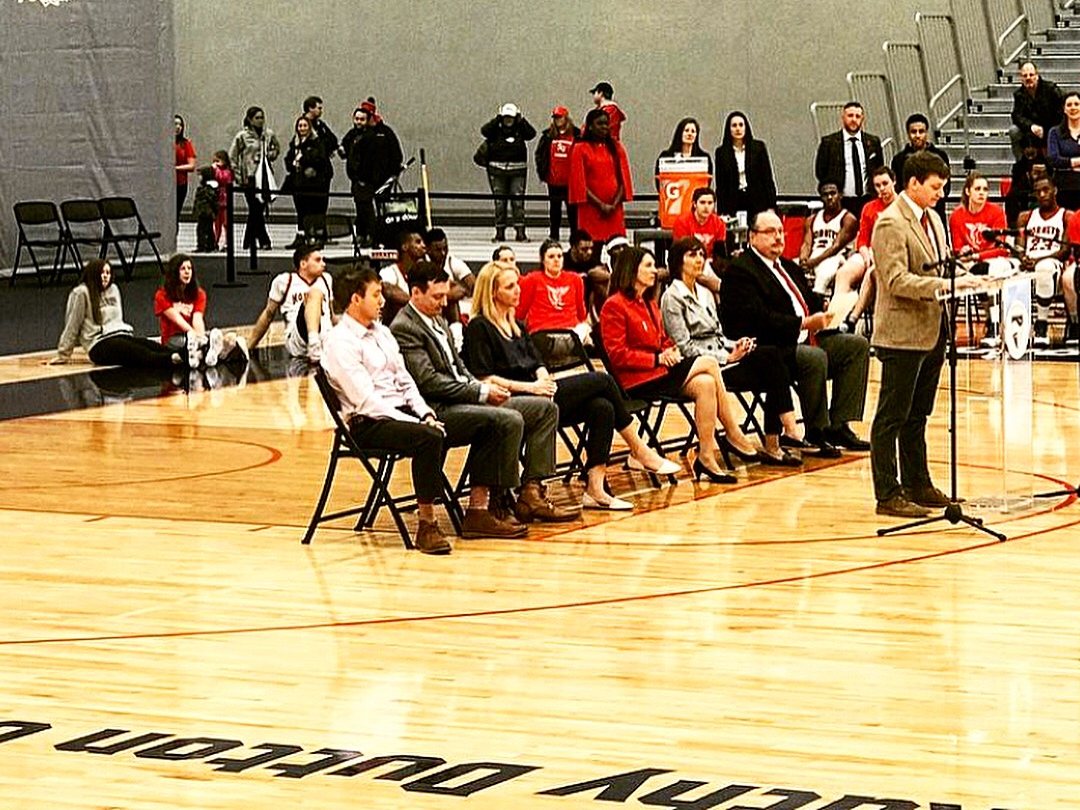 David Dutton speaking at the 2018 Dave and Kathy Dutton Court dedication, with Ryan, Adam and Aimee seated